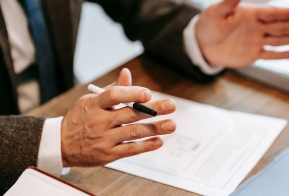 Professional discussing documents over a wooden table in an office setting.