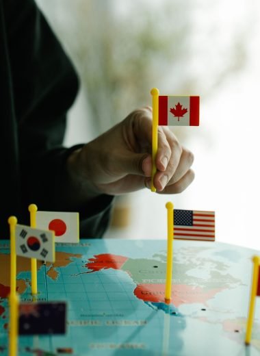 Close-up of a hand arranging mini country flags on a world map.